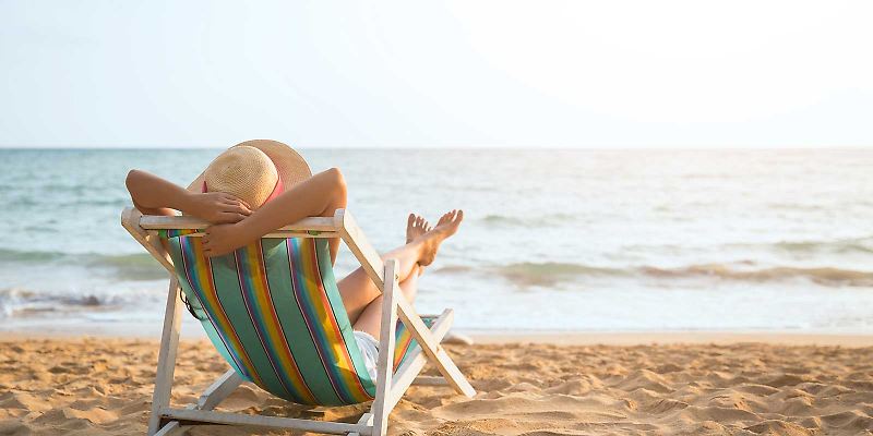 Frau entspannt am Strand in Liegestuhl