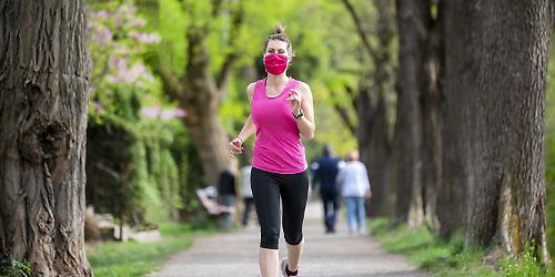 Frau joggt im Lockdown mit Maske