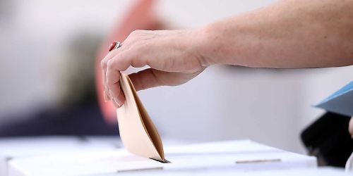 Person wirft Stimmzettel in Wahlurne