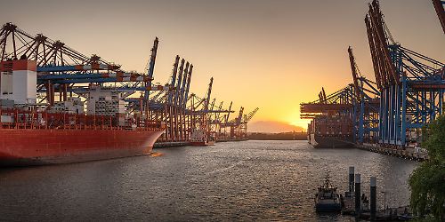 Hamburger Hafen mit Containerschiff im Sonnenuntergang