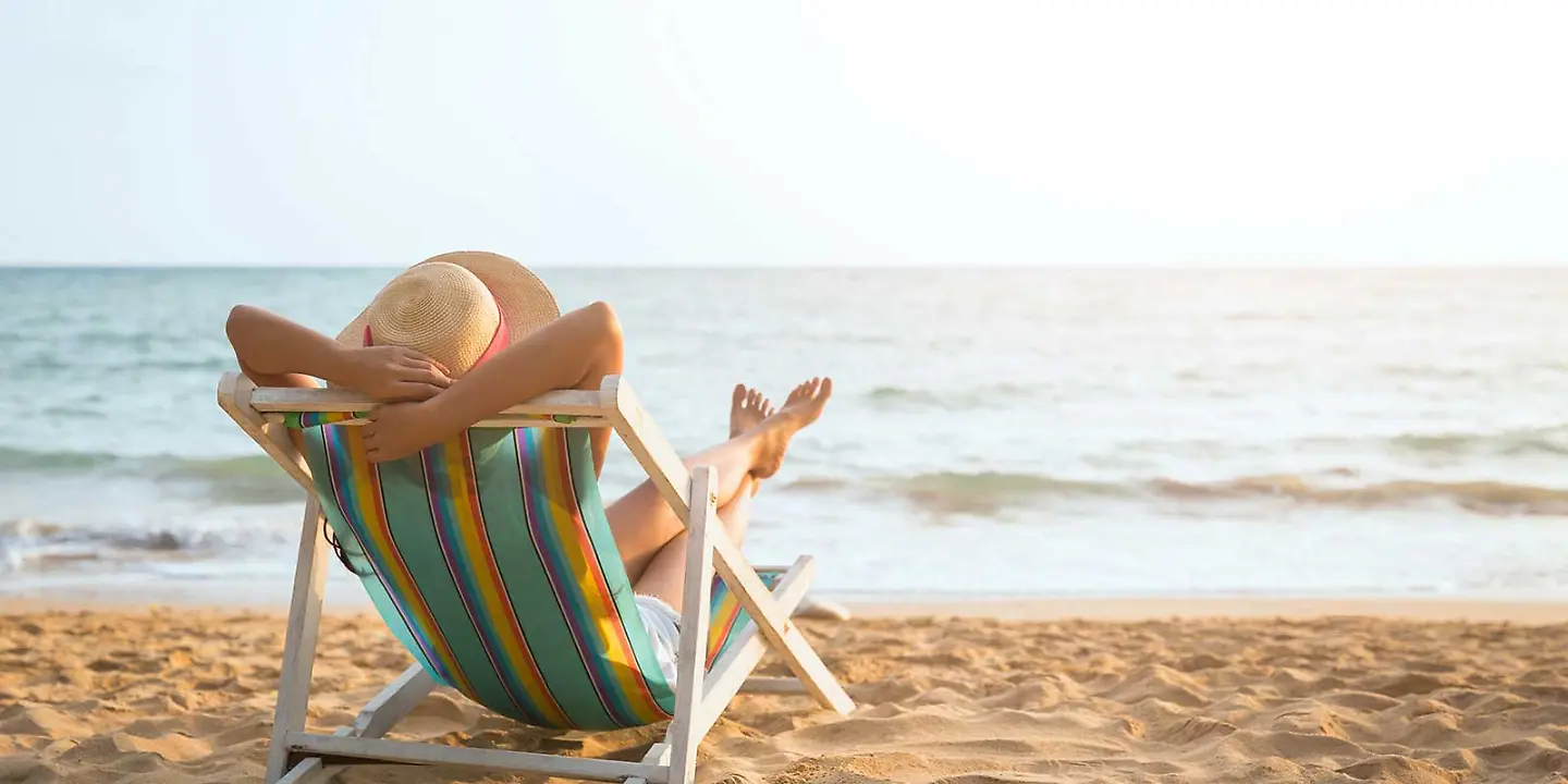 Frau entspannt am Strand in Liegestuhl